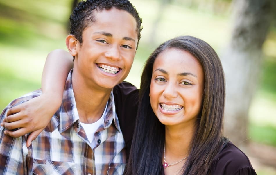 teen brother and sister hugging and smiling wearing braces